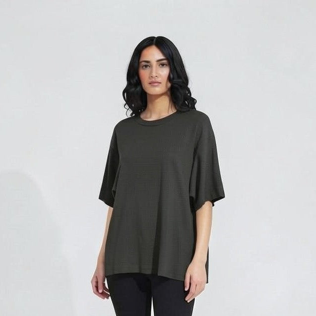 Woman wearing a dark green top and black leggings on a white background