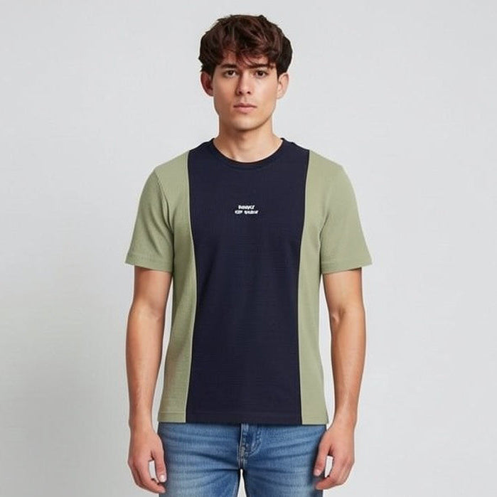 Man wearing a color-blocked t-shirt and jeans on a plain background