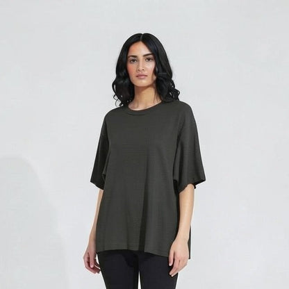 Woman wearing a dark green top and black leggings on a white background